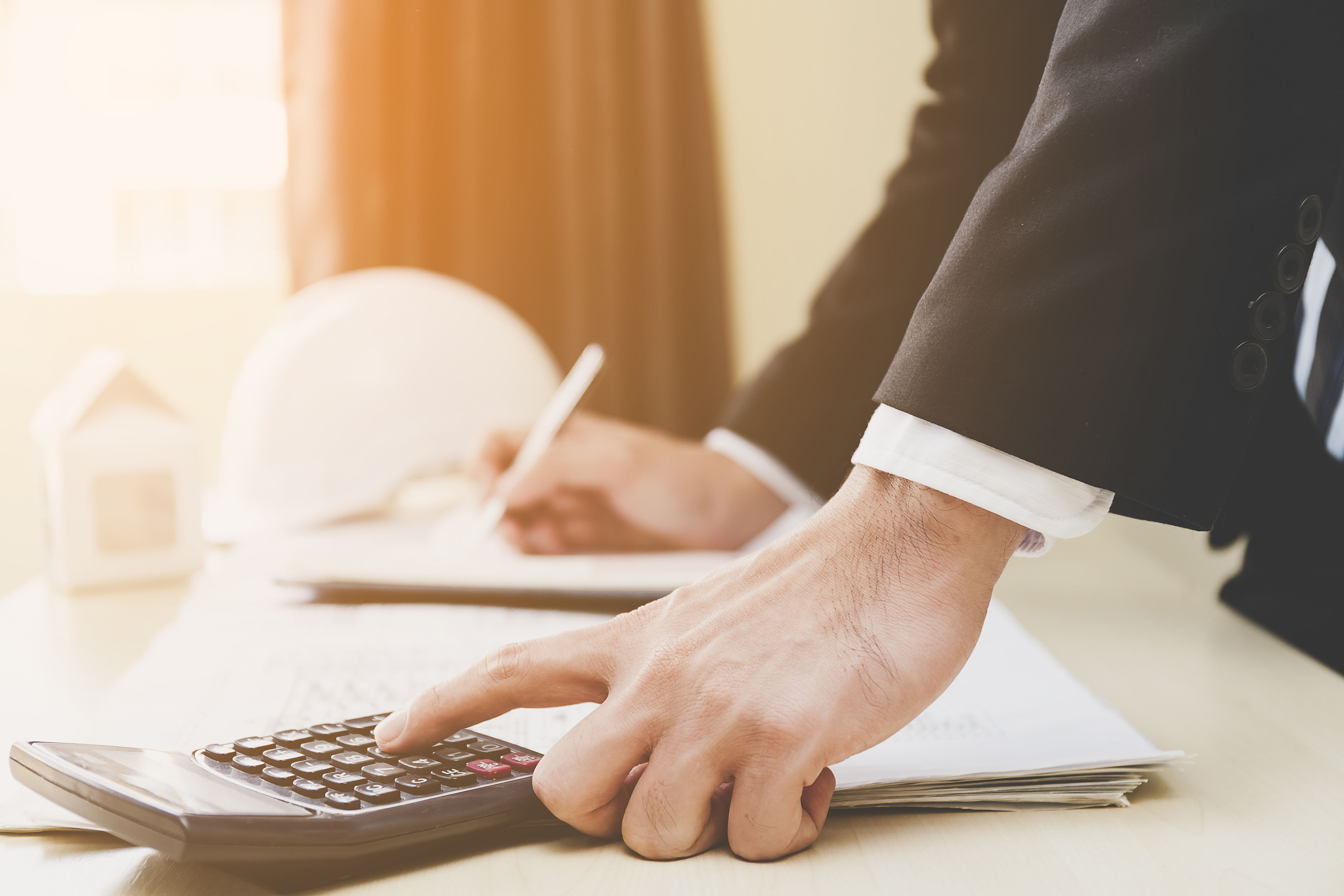 An office worker wearing business attire and using a calculator.
