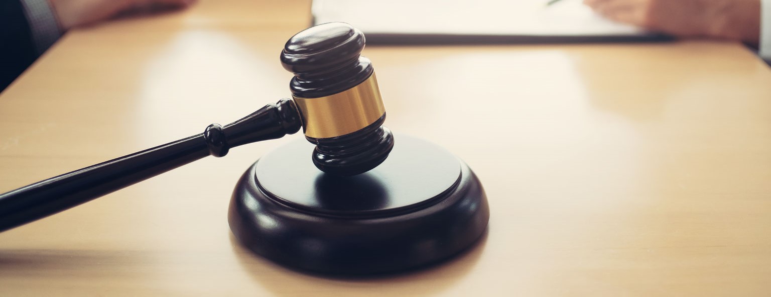A gavel on a table, with two people discussing in the background.